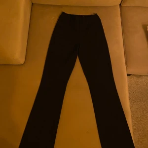 Svarta kostymbyxor från bikbok, strl 36 - Svarta kostymbyxor från BikBok med klassisk rak passform och hällor för bälte. Byxorna har diskreta bakfickor och är perfekta för en clean och stilren look. Materialet känns mjukt och följsamt, vilket gör dem bekväma hela dagen.