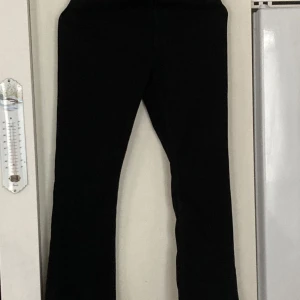 Svarta bootcut jeans från Sandro paris - Svarta jeans från Sandro Paris i klassisk bootcut-modell. Hög midja och raka ben som slutar i en lätt utsvängning. Snyggt minimalistiskt läderpatch bak i midjan. Perfekta för dig som gillar stilrena och tidlösa jeans.