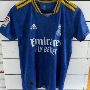 Real Madrid Benzema blå bortatröja strl 164  - Real Madrid bortatröja (third kit) från säsongen 2021/2022, i barn-/juniorstorlek (storlek 164), med Karim Benzema #9 på ryggen. Priset är förhandlingsbart, kom med bud! 