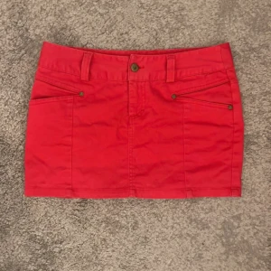 Röd kortkjol med fickor - Snygg röd kortkjol med klassisk jeanslook, fram- och bakfickor. Kjolen har knapp och dragkedja framtill och är perfekt för dig som vill ha en färgstark och enkel stil. Passar till sneakers eller boots. Passar mig som brukar ha storlek S/M💓Pris kan diskuteras 💗