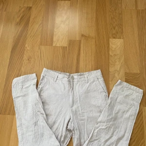 Beiga linnebyxor i bomullsblandning M - Snygga beiga linnebyxor från C i en skön blandning av linne och bomull. Byxorna har raka ben, bälteshällor, knapp och dragkedja fram samt fickor både fram och bak. Perfekta för en chill och stilren look. Nypris 399 mottpris 150 