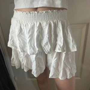 Vit volangkjol med resårmidja - Supersöt vit kortkjol med dubbla volanger och bred resår i midjan. Kjolen har en luftig känsla och är tillverkad i ett luftig tyg. Skriv vid intresse! 🌸