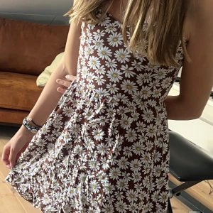 Brun blommig kortklänning med öppen rygg - Supersöt brun sommar klänning med blommor på🤎 klänning e kort och har öppen rygg. Säljer för att den e lite för liten nu🎀 även väldigt skönt material 