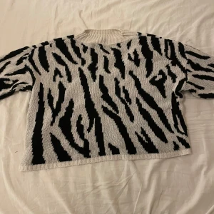 Zebramönstrad stickad tröja - Säljer  stickad tröja med svartvitt zebramönster. Tröjan har rund halsringning och långa ärmar, perfekt för dig som vill sticka ut lite extra. Supermjuk och skön att bära, passar till både jeans och kjol.
