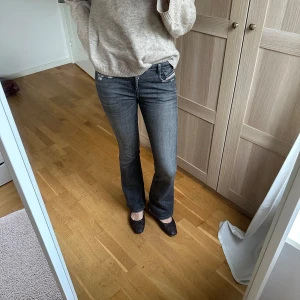 Grå bootcut jeans från Diesel - Snygga grå jeans från Diesel med bootcut passform och låg midja. Jeansen har klassiska fem fickor, slitna detaljer och tydliga sömmar. Perfekta för dig som gillar en avslappnad men ändå trendig look.