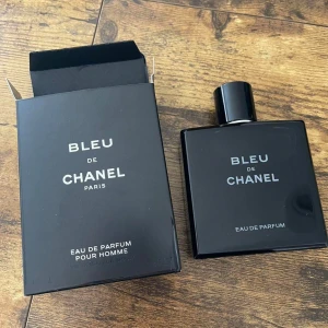 Bleu de Chanel Eau de Parfum - Bleu de Chanel Eau de Parfum för herrar i en stilren, mörkblå nästan svart, fyrkantig glasflaska med matchande kartong. Doften är modern och maskulin, perfekt för dig som gillar exklusiva och fräscha parfymer från ett ikoniskt märke.