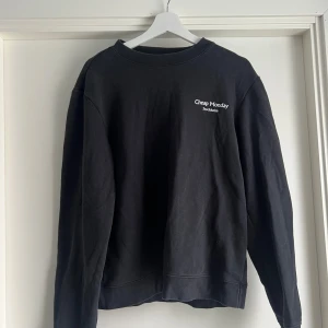 Svart Cheap Monday sweatshirt S - Svart sweatshirt från Cheap Monday med vit logga på bröstet. Klassisk rund halsringning och långärmad modell i mjuk bomull. Perfekt basic-tröja med clean look och relaxed fit. Passar till allt och är superenkel att styla.