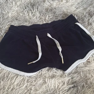 Mörkblå frottéshorts med snörning - Mysiga mörkblå shorts i mjuk frotté med vita kanter och vit snörning i midjan. Perfekta för lata dagar eller när du vill ha något bekvämt och chill. Sportig look med kort modell och elastisk midja.