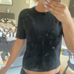 Svart basic t-shirt från Gina Tricot - En svart, enkel t-shirt från Gina Tricot i modellen Basically Basics. T-shirten har korta ärmar, rund halsringning och en rak passform. Perfekt till jeans eller kjol för en clean och stilren look.