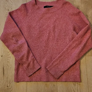 Rosa stickad tröja från Vero Moda - Mysig rosa stickad tröja från Vero Moda med rund halsringning och långa ärmar. Tröjan har ribbade muddar vid ärmslut och nederkant. 