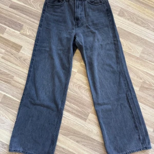 Svarta wide jeans från H&M - Snygga svarta jeans från &Denim i wide fit med riktigt hög midja. Klassisk femficksmodell och raka, vida ben. Använda en gång.