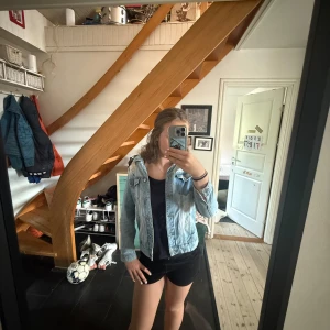 Ljusblå jeansjacka med slitningar - Säljer en ljusblå jeansjacka med  slitningar på axel, ärm och ficka. Klassisk modell med knappar framtill och bröstfickor. Jackan har blivit för liten för mig och etikett bilden fick ej plats men är från Zara 