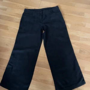 Svarta vida, raka linnebyxor  - Snygga svarta linnebyxor med breda ben och klassisk midja. Byxorna har fickor fram och bak samt hällor för bälte. Perfekta för dig som gillar en loose och trendig look. Rätt korta.