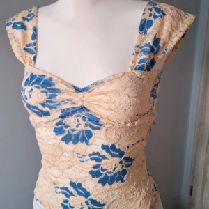 Beige spetstop med mönster  - Jag säljer min jättefina spetstopp eftersom att den aldrig kommer till användning. Använd en gång och inga defekter. Det står inget märke på den eller storlek, men jag skulle säga xs/s eftersom att den är svår att få på mig som är storlek S, men när den väl är på passar den (det kanske bara är mina breda axlar😅.)  Materialet är stretchigt. Köpt secondhand.