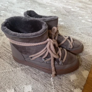 Bruna Inuikii boots med snörning - Säljer ett par bruna Inuikii boots med grova snören och mysigt foder. Skorna har en blandning av mocka och skinn, samt en platt sula. Perfekta för kalla dagar och har en riktigt chill vibe.