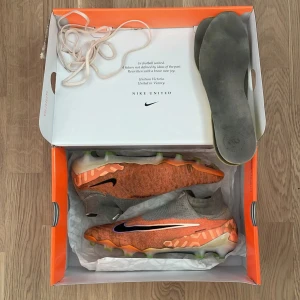 NIKE PHANTOM GX ELITE FG UNITED - GUAVA ICE/BLACK fotbollsskor. - NIKE PHANTOM GX ELITE FG UNITED - GUAVA ICE/BLACK. Skick är 7/10 inga defekter och är fortfarande jätte bra att använda! Ingen påse tyvärr men det är 100 äkta!!! Skorna säljs inte längre!! Storlek 42,5. Det är topp modellen. Pris kan diskuteras!! Om du vill byta så funkar det också. Säljer eftersom de har blivit små på mig.