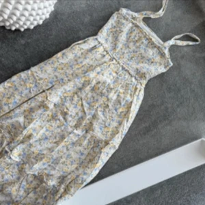 Blommig långklänning från Hollister XS - Supersöt långklänning från Hollister i blommigt mönster med tunna axelband. Klänningen har ljusa toner i vitt, blått och gult och är perfekt för varma dagar. Luftig och flowy modell som ger en romantisk vibe.