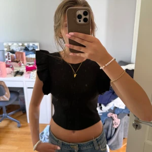 Svart croppad topp med volangärm Zara - Svart croppad topp från Zara med volangdetaljer på axlarna. Perfekt ribbad topp till sommaren.