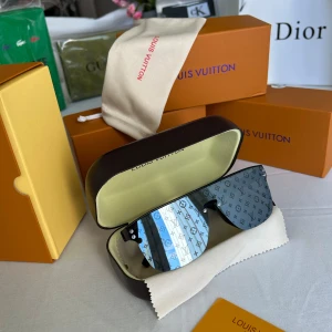 Lv glasögon  - Snygga Louis Vuitton Lv glasögon, med spegelblå och gråtonade linser i shield-modell. Glasen har LV-monogram över hela ytan och svarta skalmar. Kommer med originaletui, putsduk och box. Perfekt accessoar för dig som vill sticka ut.