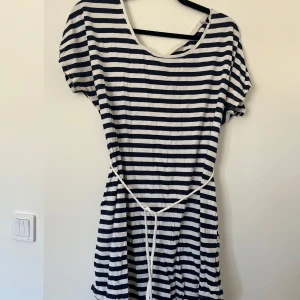 Randig kortklänning med knytband - Klänning med marinblå och vita ränder. Har fickor på vardera sida.