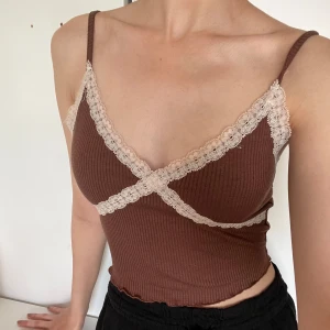 Brun ribbad linnetopp från Bershka - Supersöt brun ribbad linnetopp från Bershka med tunna axelband och ljus spetsdetalj som går i omlott över bysten. Toppen är figurnära och har en croppad passform, perfekt för att styla med höga jeans eller kjol.