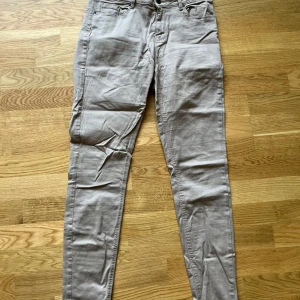 Beige skinny byxor med fickor - Snygga beige byxor i skinny fit med klassiska fem fickor och hällor för bälte. Byxorna har en smal passform och är tillverkade i ett mjukt bomullsmaterial med lite stretch för extra komfort.