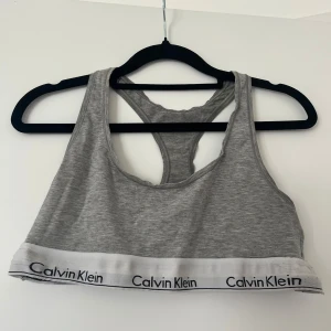 Grå bh från Calvin Klein - Säljer en grå topp från Calvin Klein med klassisk logga på det vita resårbandet nedtill.