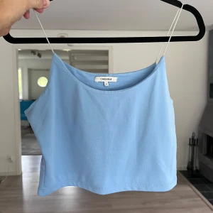Ljusblå croppad linnetopp Chiquelle - Supersöt ljusblå croppad linnetopp från Chiquelle med tunna stretchiga axelband. Enkel och stilren design som passar perfekt till sommaren. Mjuk och lätt i materialet, perfekt att matcha med jeans eller kjol. Passar bra till S/M 🩵 Önskar du veta exakta mått? Tveka inte att höra av dig!