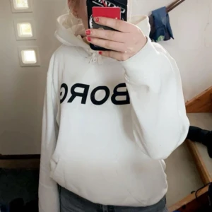 Vit hoodie från Björn Borg - Säljer en vit hoodie från Björn Borg med svart tryck över bröstet. Tröjan har huva med dragsko och en avslappnad passform. Perfekt för en chill vardagslook.