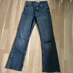 Grå bootcut jeans från Gina Tricot - Säljer ett par gråa bootcut jeans från Gina Tricot, modell perfect jeans. Byxorna har hög midja, klassisk femficksdesign och en liten sliten detalj på ena benet. Perfekta för dig som gillar en lite vidare passform nertill.