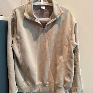 Beige fleece-tröja med halv dragkedja från Zara - Säljer en beige fleece-tröja från Zara med halv dragkedja och hög krage. Tröjan har lång ärm och ribbade muddar vid ärmslut och nederkant. Perfekt för lager-på-lager och enkel att matcha med olika outfits.