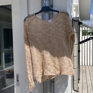 Beige stickad tröja från Monki - Säljer en beige stickad tröja från Monki i storlek XS/S. Tröjan har ett grovmaskigt, luftigt mönster och långa ärmar. Perfekt för lager-på-lager och en chill stil. Rund halsringning och avslappnad passform.