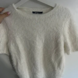Vit fluffig stickad tröja från Gina Tricot - Supermjuk och fluffig vit stickad tröja från Gina Tricot. Tröjan har korta ärmar och rund halsringning, perfekt för lager-på-lager eller som statement-piece. Enkel att styla till olika looks.