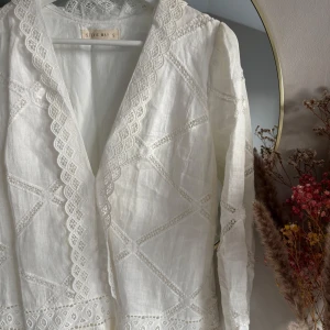 Vit spetsklänning från Stevie May - Passar fint som student klänning! Romantisk vit klänning från Stevie May med v-ringning och vackra spetsdetaljer. Klänningen har lång ärm, markerad midja och volangkant nertill. 