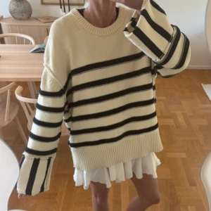 Randig stickad tröja från Dagmar - Säljer en beige/cremevit och svart stickad tröja från Dagmar med breda och smala ränder. Tröjan är väldigt oversize så passar även större storlekar, använd men i gott skick