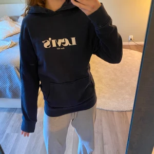 Mörkblå hoodie från Levi's - Säljer en mörkblå hoodie från Levi's med vit logga på bröstet och ficka framtill. Tröjan har huva och långa ärmar. Klassisk och enkel design med mjukt material. Pris kan alltid diskuteras. Den har inga snören i huvan men inget som märks (bild 2), fint skick. Säljer pga att den knappt kommer till användning av mig. Skriv vid fundering osv❣️