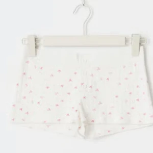 Vita shorts med rosa rosett-mönster och knappar - Söta vita shorts med små rosa rosetter och knappar framtill. De har bred ribbad midja och är tillverkade i mjukt bomullsmaterial. Perfekta för en avslappnad sommarlook. Original pris 100kr❤️