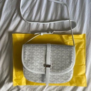 Vit axelremsväska - Säljer en helt oanvänd vit axelremsväska. Den har alla fina detaljer. Jag har aldrig använt den. Passar för många storlekar. Priset kan diskuteras.