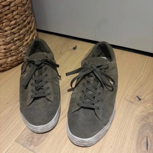 Olivgröna sneakers från Polo Ralph Lauren - Säljer ett par olivgröna sneakers från Polo Ralph Lauren i mocka med snörning och vit sula. Klassisk design med rund tå och diskret logga på sidan. Perfekta för en stilren vardagslook.