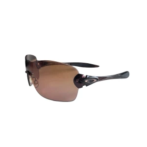  solglasögon från Oakley compulsive - Snygga solglasögon från Oakley med bruna, halvbågade linser och svarta skalmar. Sportig design med Oakleys logga på sidan. Perfekta för dig som gillar en aktiv livsstil och vill ha stilrena glasögon med bra passform. Finns märken på glaset, se bilder
