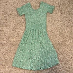 Unik klänning - Söt grön klänning från Uniq Young med små vita blommor och korta ärmar. Klänningen har smock upptill och ett lätt utställt kjolparti. Perfekt för vår och sommar!