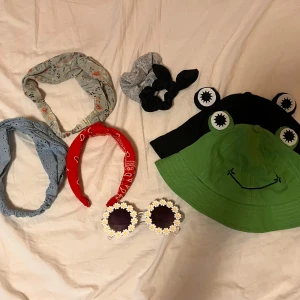 Bundle av olika accessoarer 🥝💚 - Säljer en grön och svart bucket hat med broderat grodansikte och utstickande ögon, samt fem diadem i olika färger och mönster. Perfekt för att addera färg och lekfullhet till din stil !! 🥳