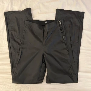 Svarta ”läder” byxor från Bubbleroom x Moa Mattsson - Snygga svarta byxor från Bubbleroom x Moa Mattsson, byxorna är i strl 38 och har en boot cut form. De är gjorda i ett glansigt material lite som fejk läder och sitter snyggt på. 
