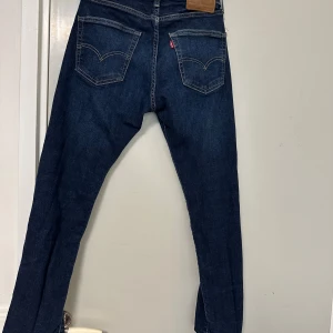 Levis 511 mörkblå jeans - Mörkblå Levis 511 jeans med klassiska fem fickor och raka ben. Jeansen har en snygg tvätt och tydliga kontrastsömmar. Passar perfekt till vardags och har en ikonisk Levis-lapp bak i midjan.