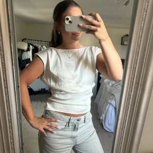 Vit croppad linnetopp - Säljer en stilren vit croppad linnetopp med korta ärmar och rund halsringning. Perfekt för varma dagar och enkel att matcha med olika outfits. Snygg och enkel design som passar till mycket.