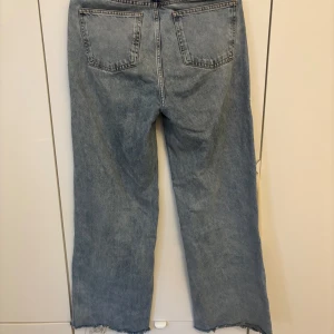 Tower Wide jeans från Never Denim - Snygga ljusblå jeans från Never Denim by Bik Bok i modellen Tower Wide. Byxorna har raka, vida ben och råa, avklippta benslut för en trendig look. Klassisk femficksmodell och hög midja. Perfekta för dig som gillar en avslappnad stil.