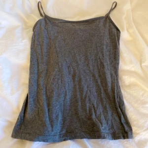 Grå linnetopp från Lindex - Säljer en enkel och stilren grå linnetopp från Lindex. Toppen har tunna axelband och rak passform, perfekt att matcha med jeans eller kjol. Mjuk och skön bomullskänsla. I storlek S