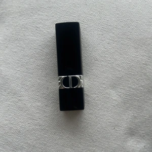 Dior Rouge läppstift 028 Actrice - Säljer ett Dior Rouge läppstift i nyansen 028 Actrice. Hylsan är svart med silverdetaljer och har den klassiska CD-loggan. Färgen är en elegant, mellanrosa ton med satin-finish. Perfekt för dig som vill ha en lyxig touch till din sminkväska.  Kommer utan förpackning, oanvänd och otestad, om du köper fler av dessa läppstift kan jag tänka mig bättre pris. Rensning inför flytt. Vissa märken på själva skalet på läppstiftet kan förekomma då jag förvarat alla i samma låda 