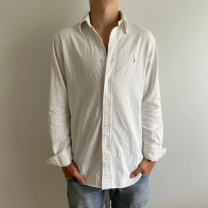 Vit skjorta från Ralph Lauren - Klassisk vit skjorta från Ralph Lauren med broderad logga på bröstet. Skjortan är i jätte fint skick och har inga fläckar eller liknande. Perfekt inför sommaren☀️✅Nypris:1200kr mitt pris: 449kr Det är bara att skriva om du har några funderingar priser är aldrig hugget i sten🪨🤩👍