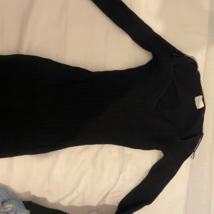 Svart ribbad långärmad klänning, pris kan diskuteras  - Snygg svart ribbad klänning med lång ärm och figurnära passform. Klänningen har v-ringad hals och är tillverkad i ett stretchigt material som sitter tight och markerar siluetten. Perfekt för dig som gillar en stilren och enkel look. Storlek M, sitter bra på kroppen, inte för lång eller för kort jag är ca 175 och den är lite över anklarna, bekväm under höst/ vinter